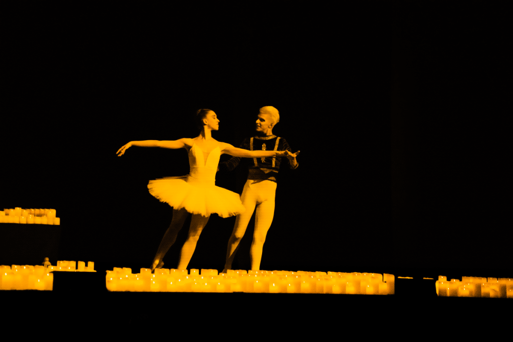dos bailarines de ballet danzando en un escenario lleno de velas